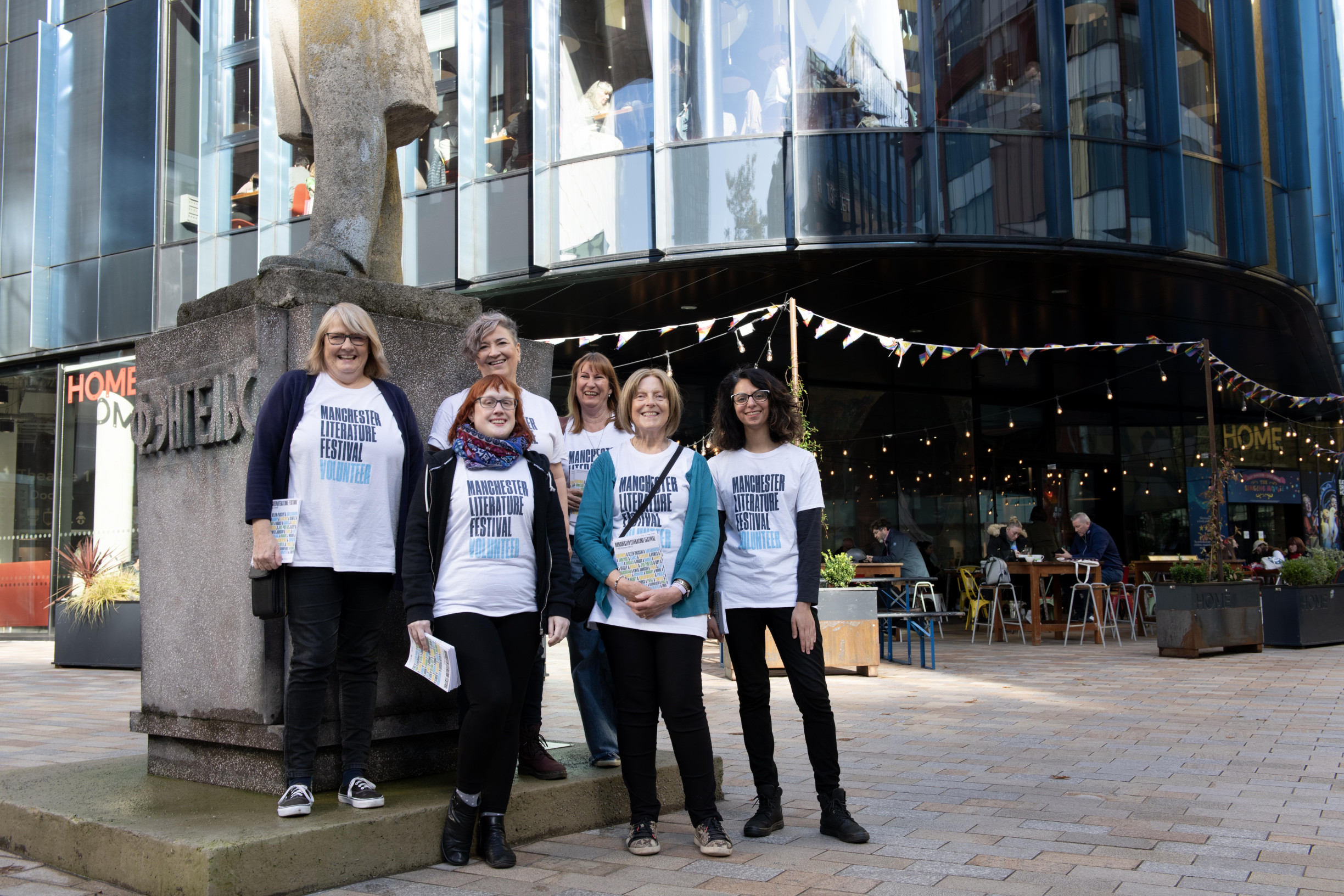 6 volunteers wearing Manchester Literature Festival T-shirts outside HOME